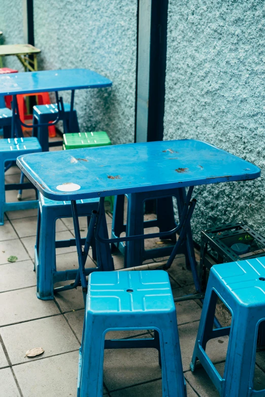 four blue metal tables and one black plastic stools