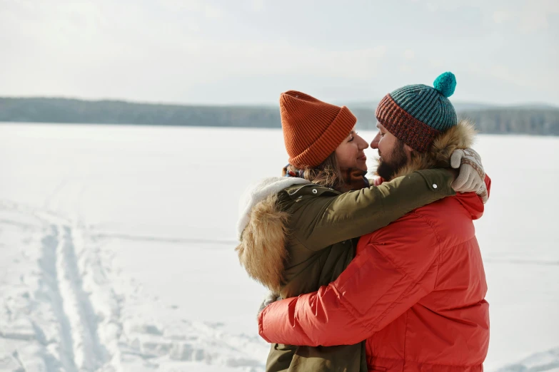 a couple are standing in the snow holding each other