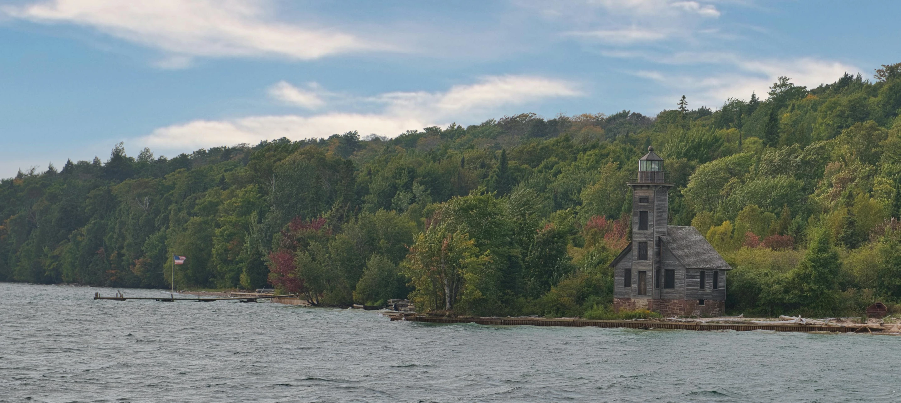 an old house sitting on top of a tree covered hill