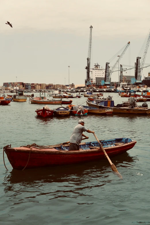 a person paddling a row boat in front of a harbor filled with boats