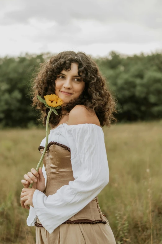 an attractive woman standing with a flower in her hand