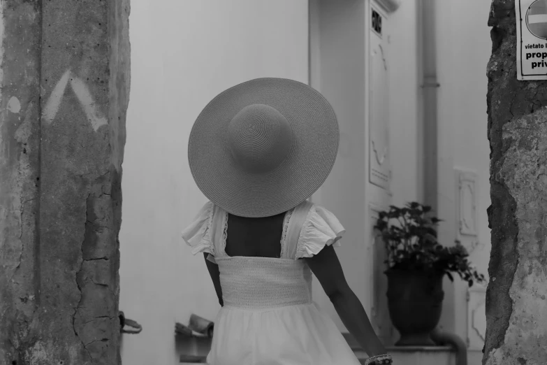 a woman with a big hat walking down the street