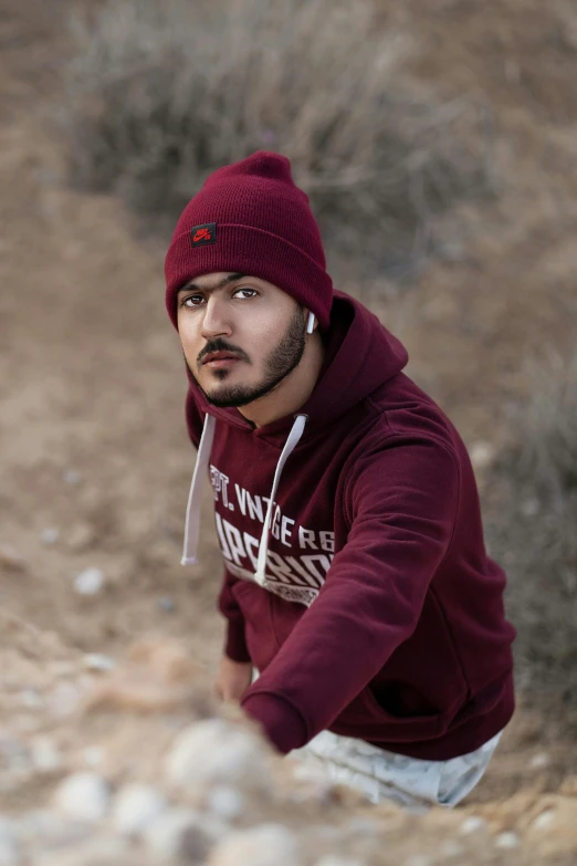 a man in a hoodie squatting on some rocks