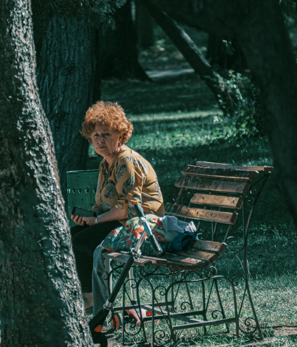 an old woman sitting on a bench under a tree