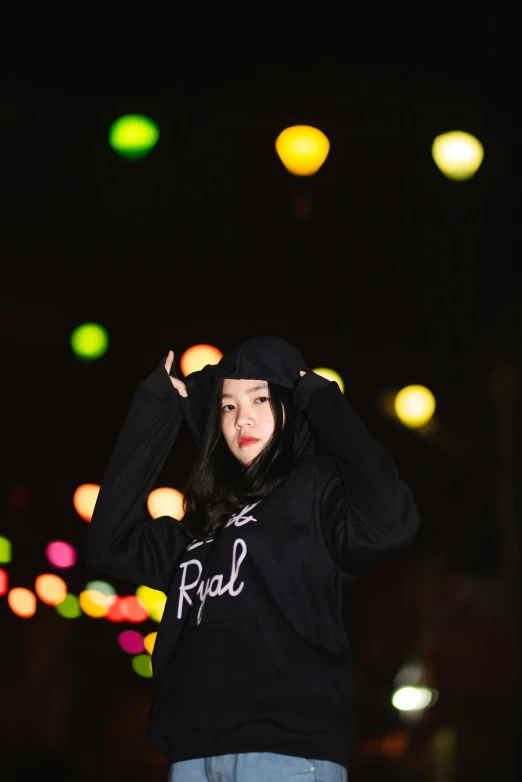 a girl posing at night wearing black hoodie and cap