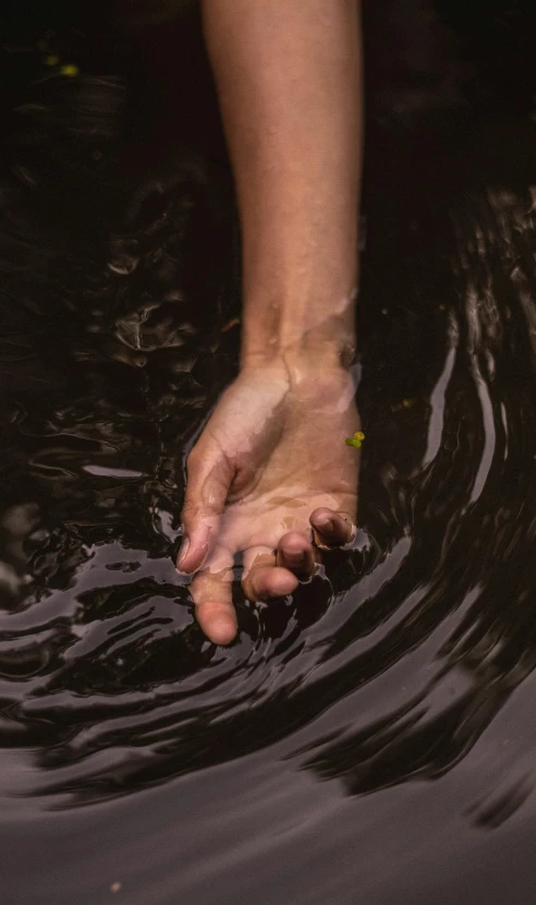 a person holding out their hand above the water