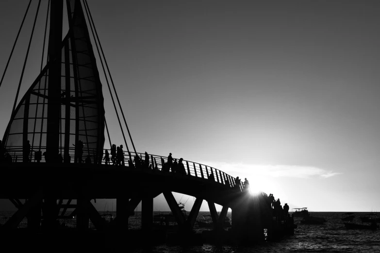 several people are gathered under a structure on a pier