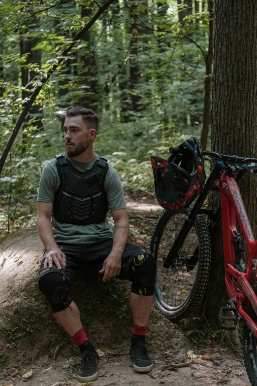 a man is sitting next to a red bicycle