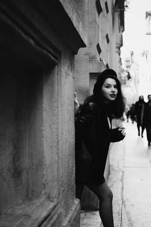 a woman wearing black leaning against the side of a building