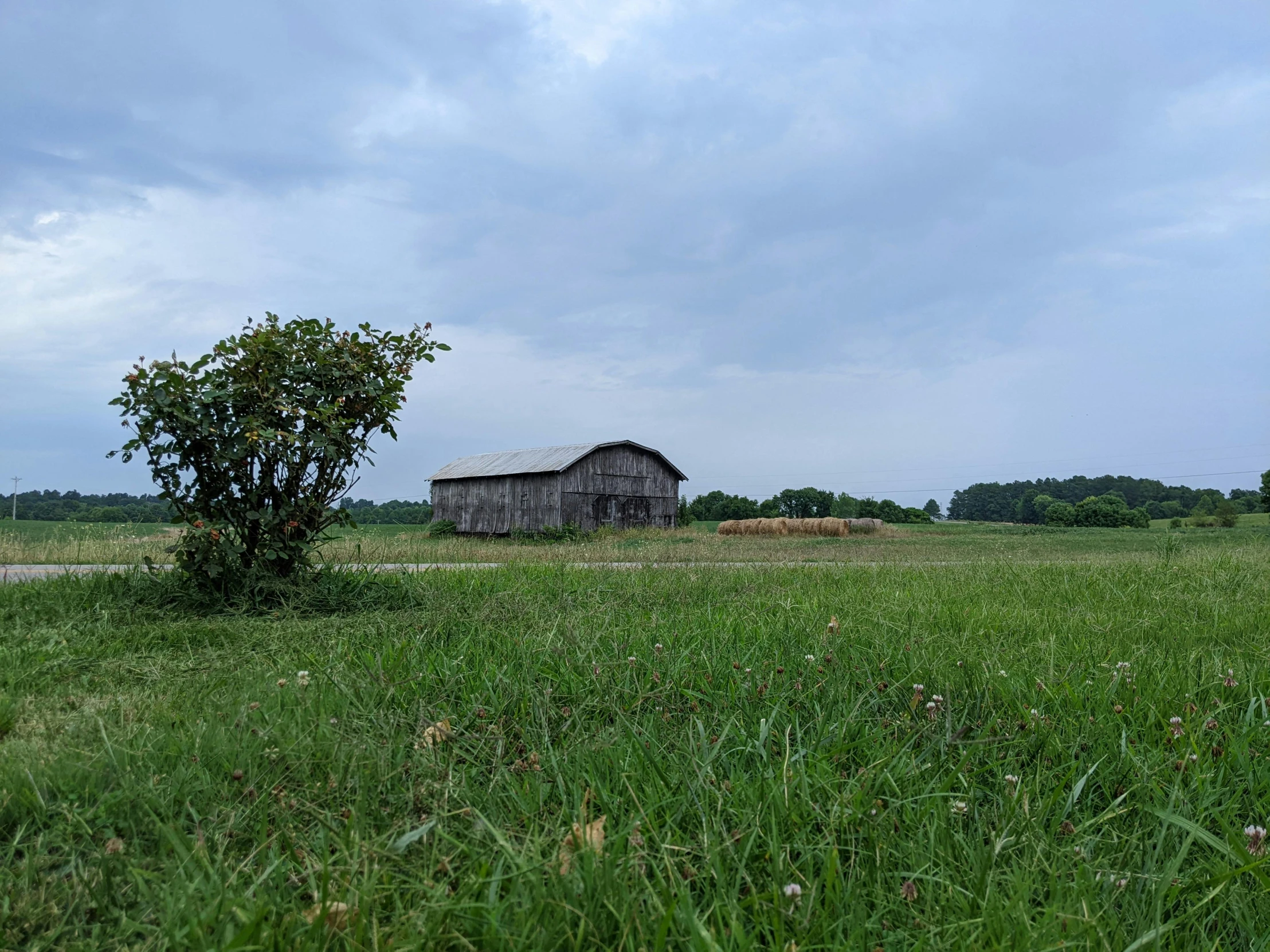 an old run down barn stands in the middle of a field