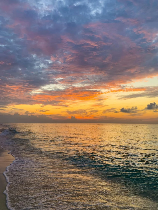 the ocean and beach in front of a sunset