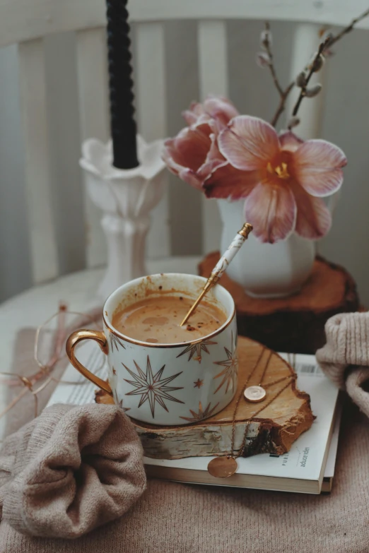 cup of liquid and book on table with flowers