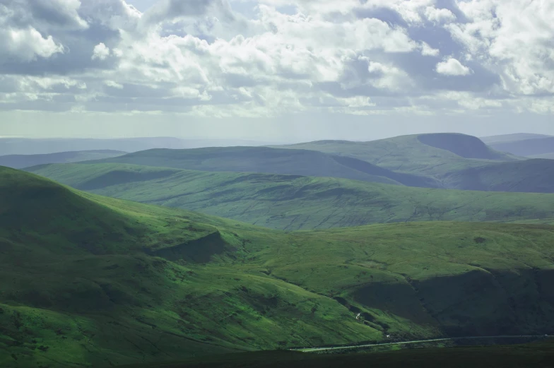 a green valley and mountain side view under cloudy skies