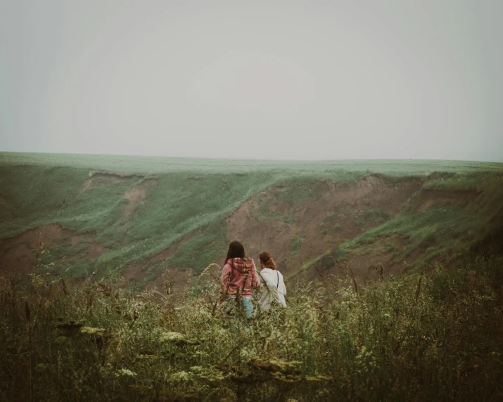 two young women stand near each other in a field