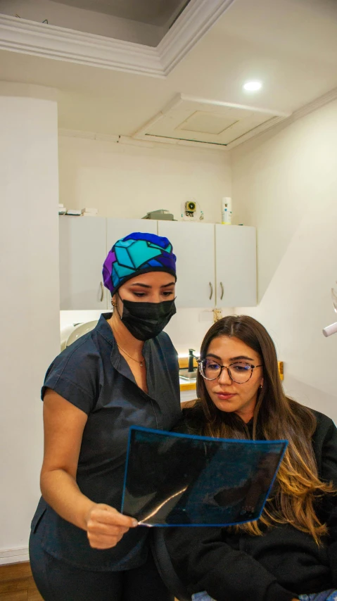 two women with face masks look at a clipboard