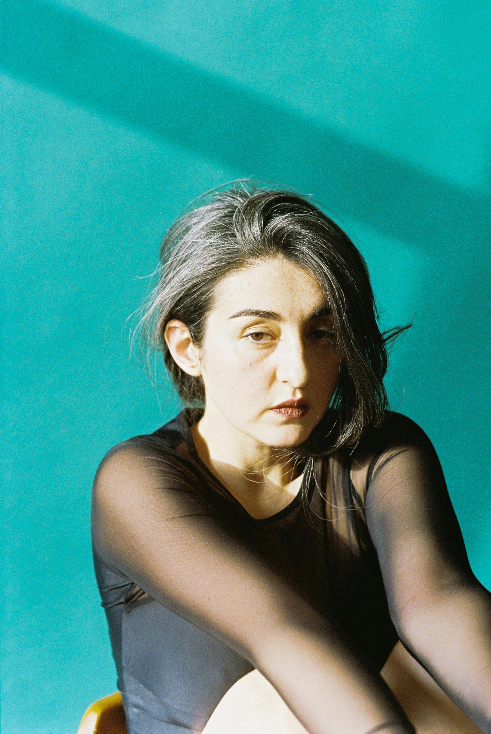 a woman wearing a black top and pants is sitting on a yellow chair