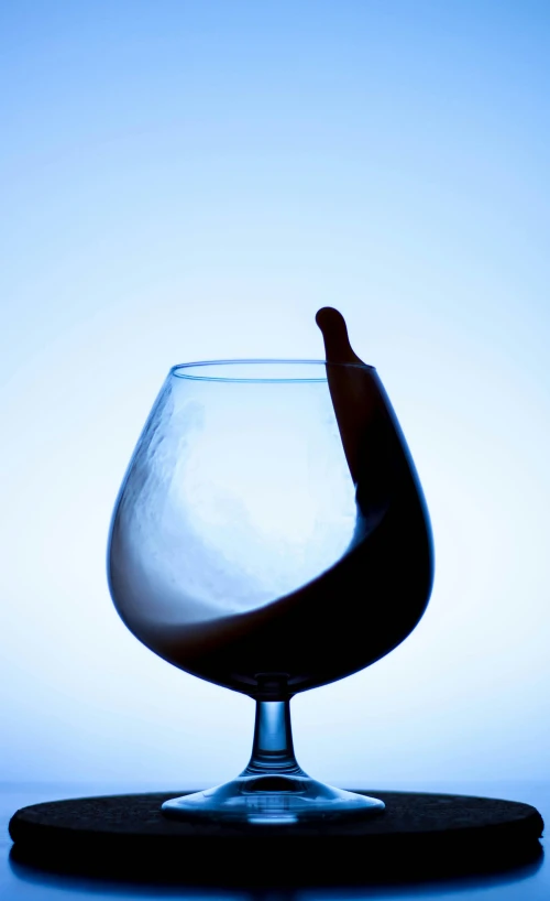 a glass with a beverage in it, on top of a blue background