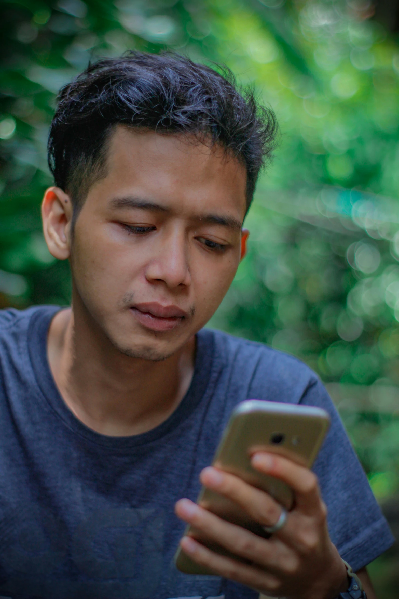 a man looks at his phone in the forest