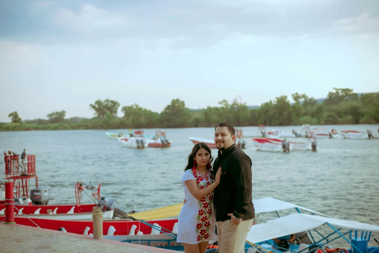 couple emcing while standing by boat docks with many boats in the water