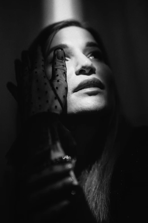 woman wearing a black and white image covering her face with one hand