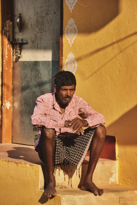 a man sitting on steps wearing a plaid shirt