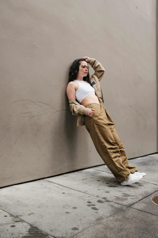 a woman leaning against a wall with her foot on her head
