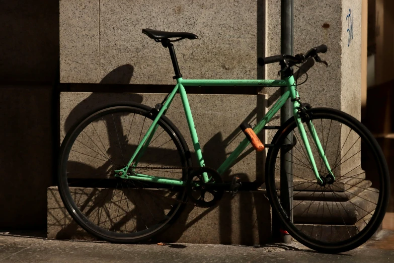 a green bicycle leans against a stone wall