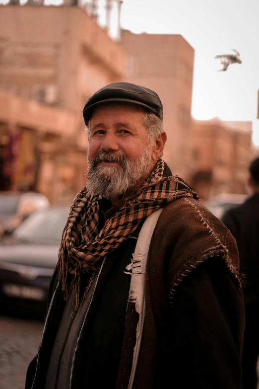 an older man with a beard smiles and looks at the camera