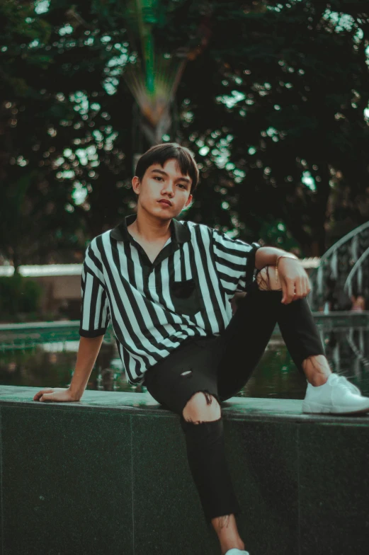 a boy sitting on the edge of a fence posing