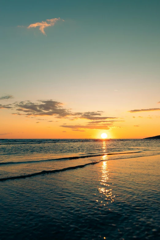 the sun setting behind the ocean on a beach