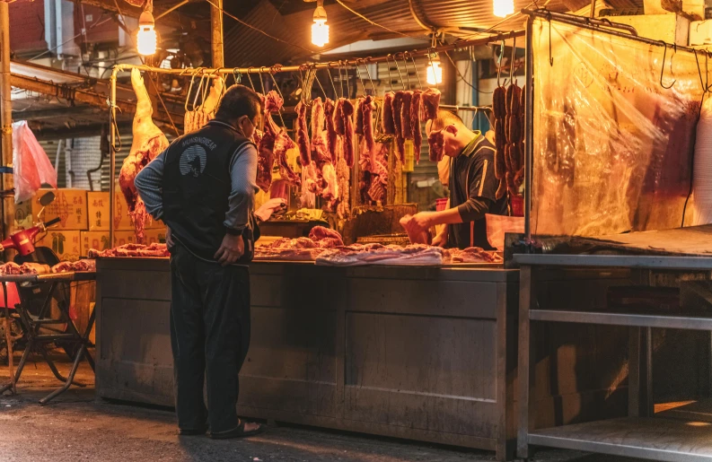 a man standing in front of a meat stand at night