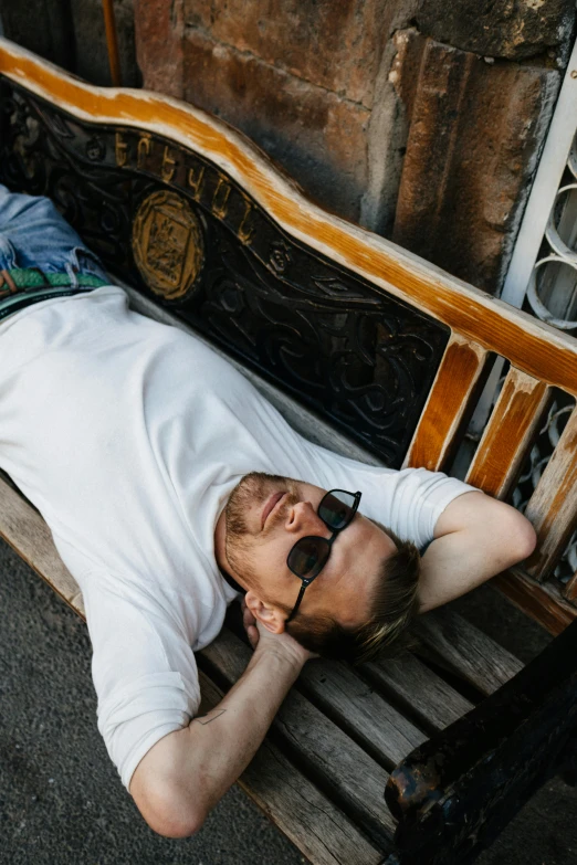 a man lying on a bench with sun glasses