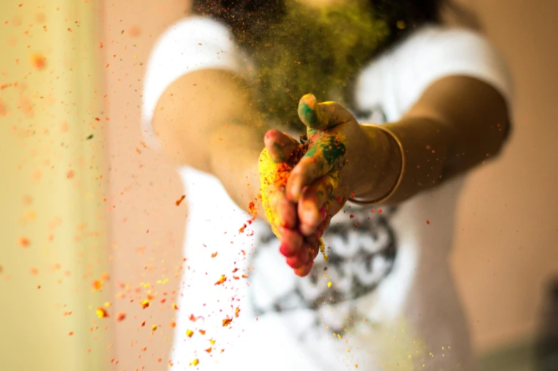 someone covered in yellow powder throwing it up into the air