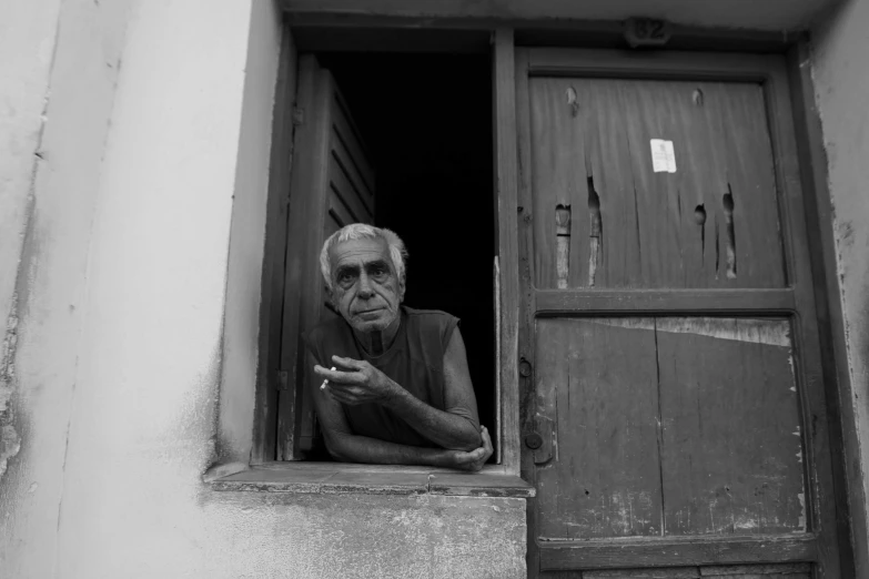 an old man is looking out of the window of a small house