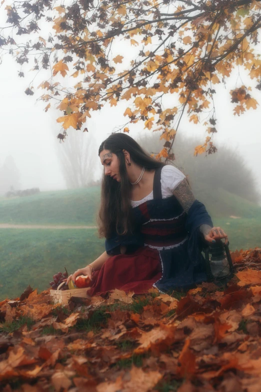 the young woman sitting under a leaf filled tree