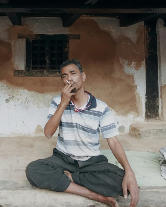 a man sitting on the floor smoking a cigarette