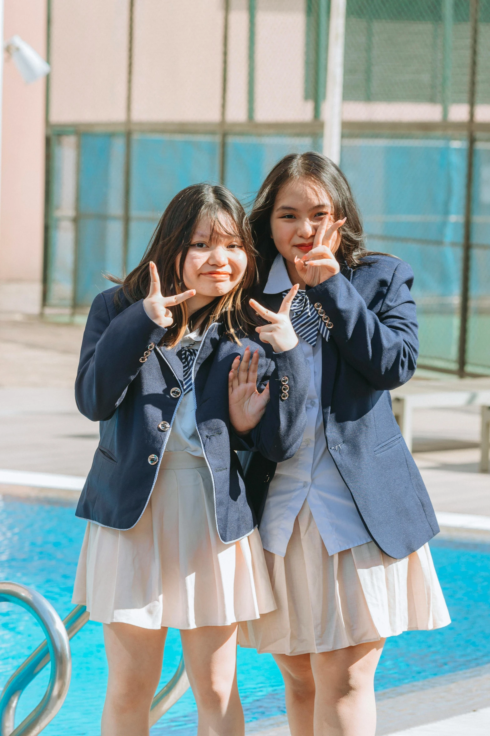 two girls posing next to a pool on the street