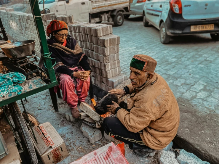 a pair of people sitting on the side of a street