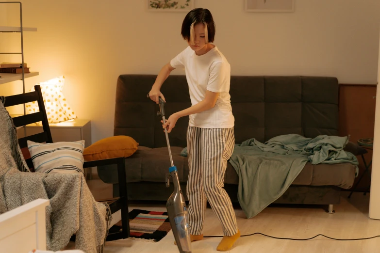 a young person in a living room holding an electric vacuum