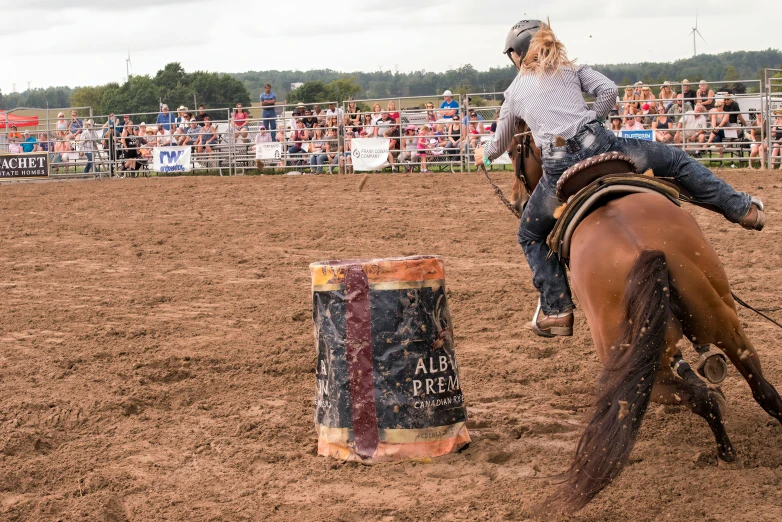 a girl riding on the back of a horse over an obstacle