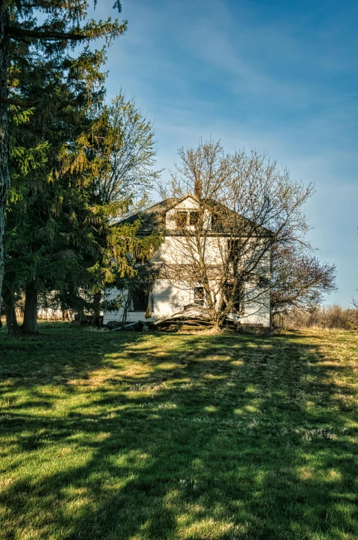 a house sits in the middle of the meadow on a sunny day