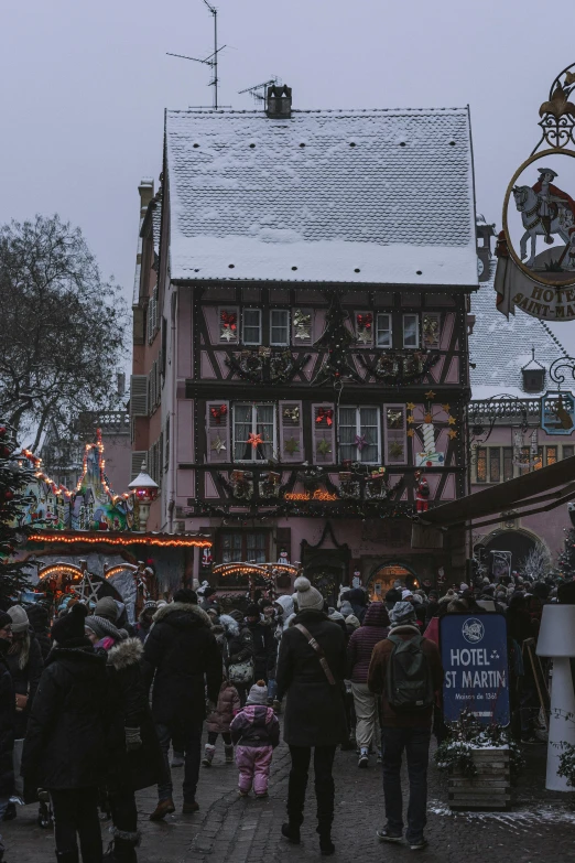 people walking down a small town street lined with christmas lights