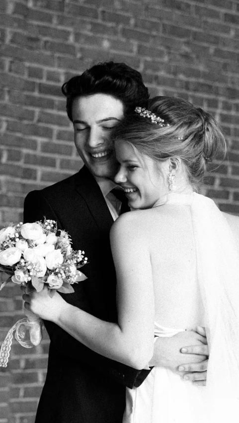 a bride and groom standing in front of a brick wall