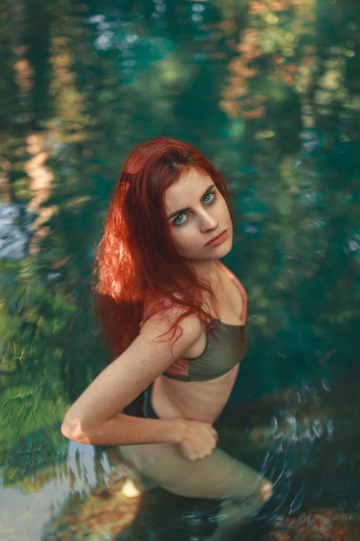 a woman with red hair and a dark top standing in a pool of water