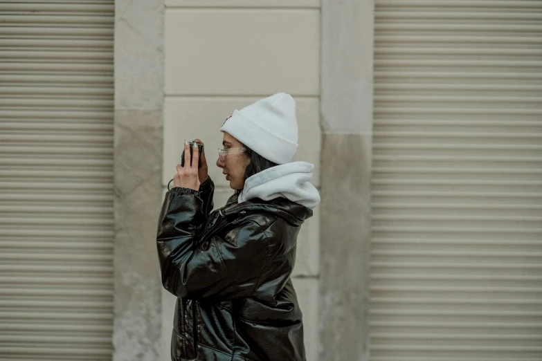 a woman in a leather coat stands by a door