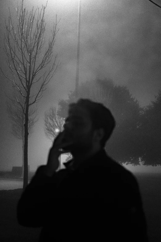 silhouette of a man on his cellphone in the fog