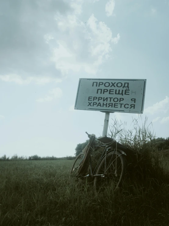 a sign and a bicycle in a field