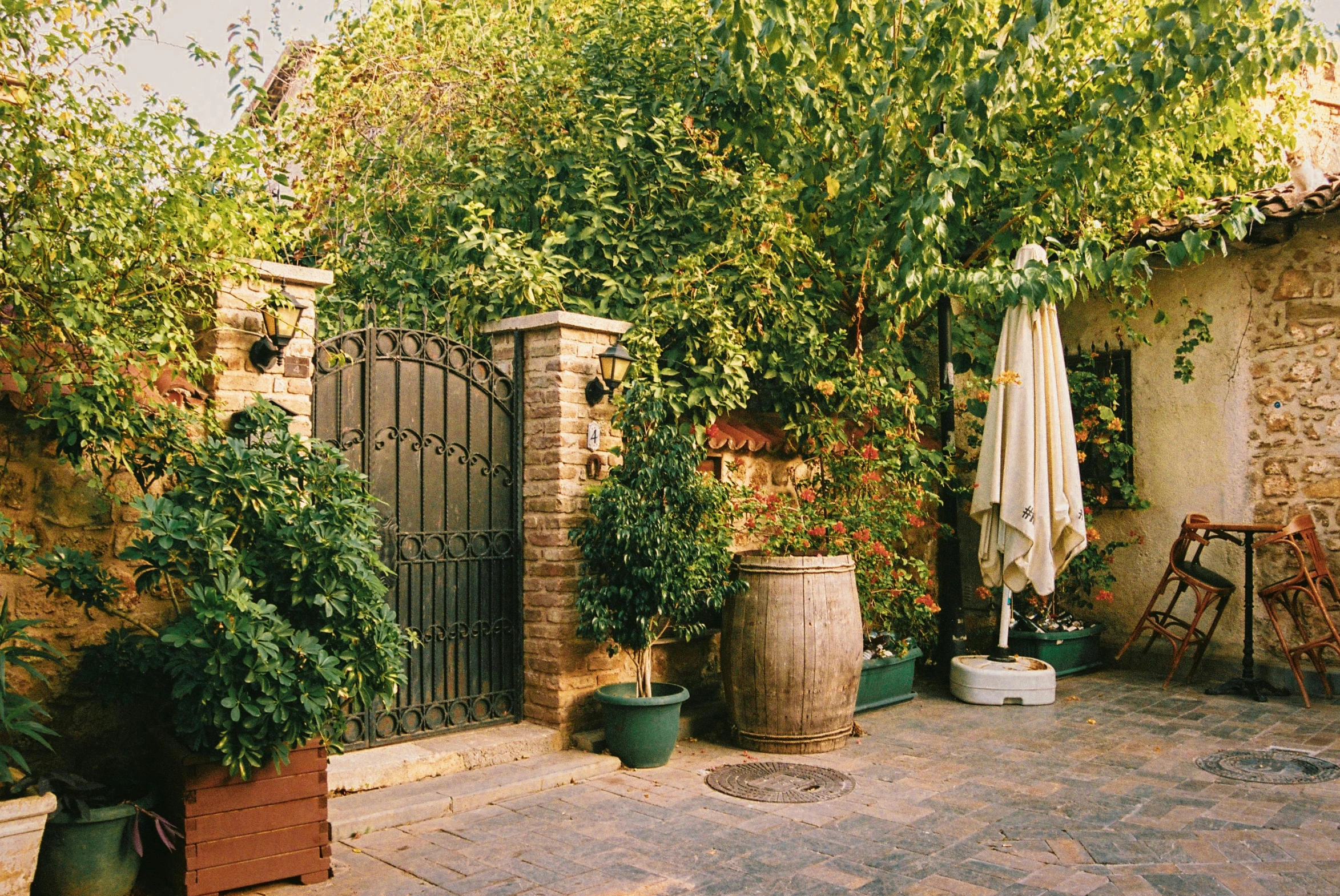 a stone patio with potted plants and table outside of it