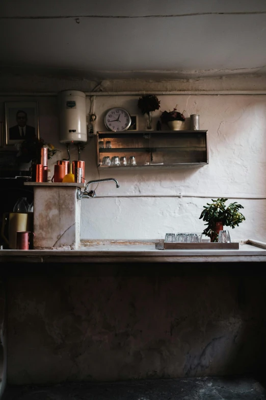 a sink under a shelf filled with bottles and bowls