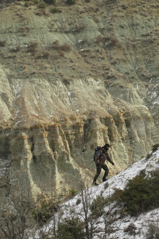 a person hiking on the side of a mountain covered in snow